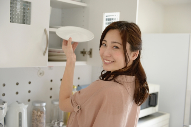 女性がお皿を棚に入れる写真